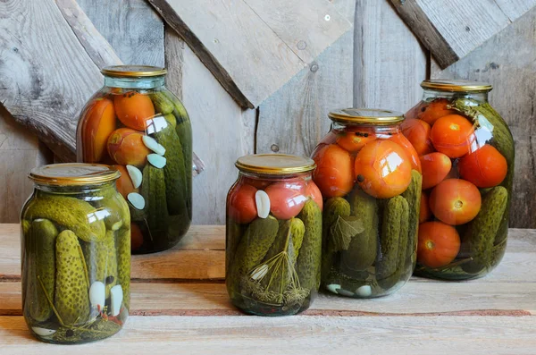 Glazen potten met Ingeblikte tomaten en komkommers. Houten achtergrond — Gratis stockfoto