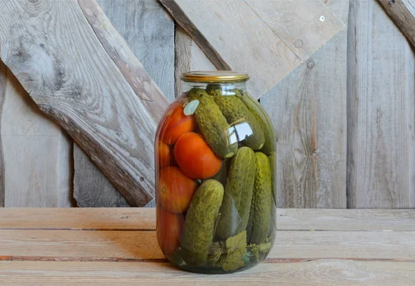 Tomates y pepinos enlatados en un frasco de tres litros. Fondo de madera — Foto de Stock