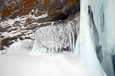 Baykal, buz blokları ve sahil kayalar üzerinde buz sarkıtları, sahilinde dalgaların buz sıçraması.