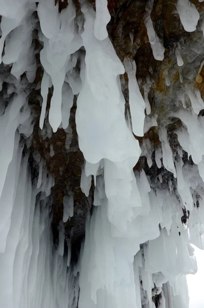 Eisspritzer von Wellen an den Ufern des Baikalsees, Eisblöcke und Eiszapfen an den Küstenfelsen. — Stockfoto