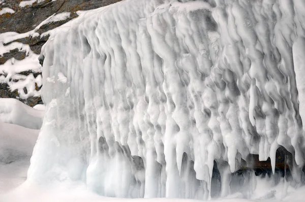 Eisspritzer von Wellen an den Ufern des Baikalsees, Eisblöcke und Eiszapfen an den Küstenfelsen. — Stockfoto