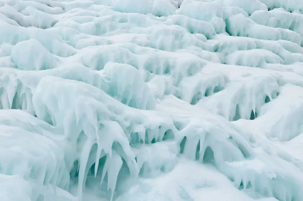 Ghiaccio spruzzi di onde sulle rive del Baikal, blocchi di ghiaccio e ghiaccioli sulle rocce costiere . — Foto Stock