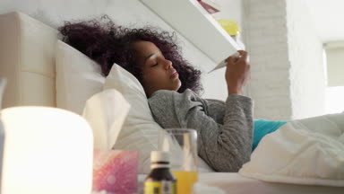 Termometre ve Tablet kullanarak yatakta ateşli kız