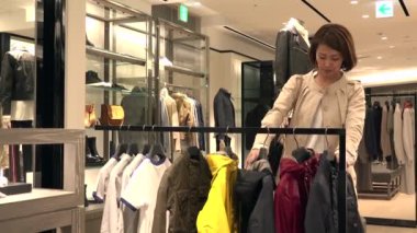 Asya insanlar moda ürünler ve aksesuarlar için alışveriş. Japon kadın lüks mağaza alışveriş merkezi içinde. Anne Çocuk ceket deposundaki alış ve satış asistanı yardım ve destek için konuşuyor