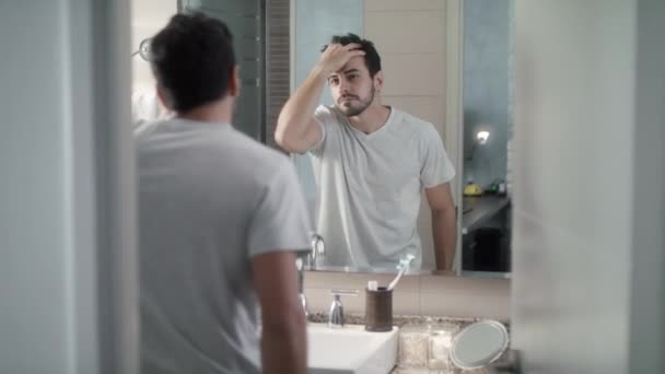 Jovem preocupado com a perda de cabelo e olhando para o espelho — Vídeo de Stock