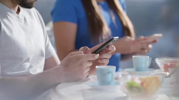 Partners met behulp van de telefoon terwijl het eten van ontbijt samen — Stockvideo