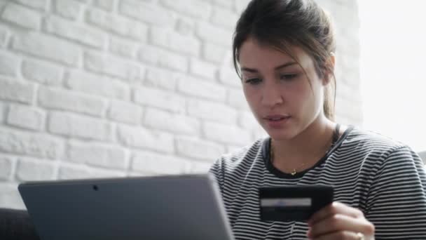 Молодая женщина делает покупки в Интернете с помощью кредитной карты и ноутбука — стоковое видео