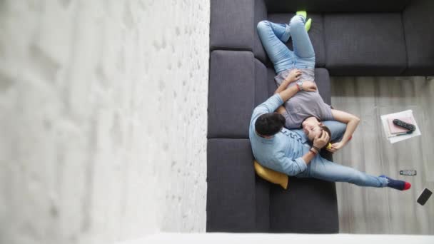 Jovem casal abraçando e rindo no sofá — Vídeo de Stock