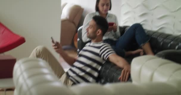 Feliz casal hispânico usando smartphones no sofá em casa — Vídeo de Stock