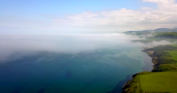 無人島男空中観突然霧と霧の海から到着し 気象条件の変化と伝統的な英国の風景の皮の近くの海岸で空を飛んでいます — ストック動画