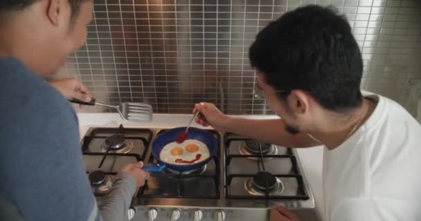 Gay män äter frukost matlagning ägg i hem kök — Stockvideo