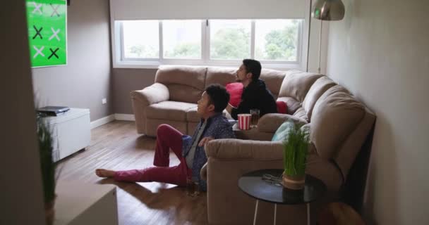 Feliz casal gay assistindo jogo de esportes na TV em casa — Vídeo de Stock