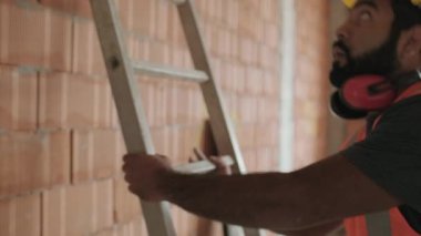 Kendine güvenen insanlar inşaat sitesinde çalışıyor. Apartman içinde yeni evde iş yerinde mutlu İspanyol adam portresi. Merdiven kullanma ve kameraya gülümseyen profesyonel latino işçi. Ağır çekim