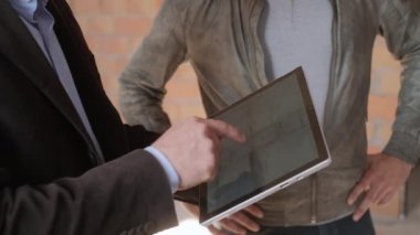 Yeni binada müşterilerle konuşurken iş adamı. İnşaat alanında müşteriler ile çalışan adam. Ev planları tablete karı koca gösterilen mühendis. Yeni ev alıcılar olarak genç çift