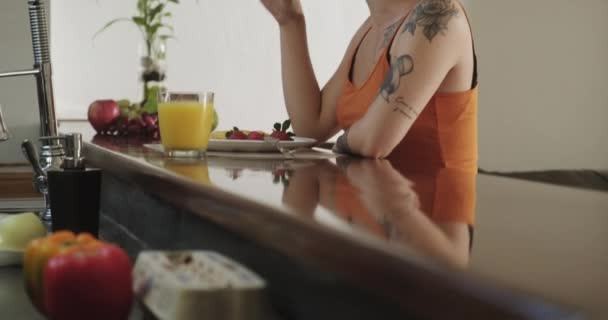 两个女同志在家 女孩吃水果和零食吃 伙伴在手机上交谈 快乐的同性恋家庭生活方式 年轻女性 同性恋女孩 同性伴侣为爱情接吻 — 图库视频影像