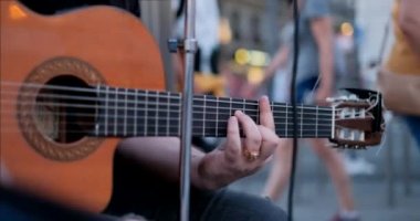 Genç adam kaldırımda gitar çalıyor ve şarkı söylüyor. Madrid, İspanya, Avrupa'da müzik aleti ile sokak sanatçısı. Şarkıcı, müzik ve sanat. Dizeleri ve parmakların yakın çekim