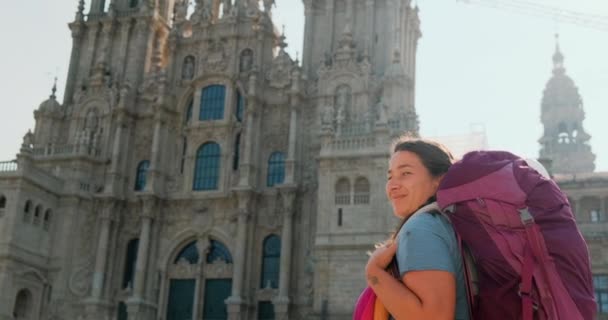 カミノ サンティアゴの終わりにスペインの町 サンティアゴ コンポステーラのカメラを見て幸せな女性巡礼者の肖像画やセントジェームズの道 スペインで微笑む女性 スローモーション — ストック動画