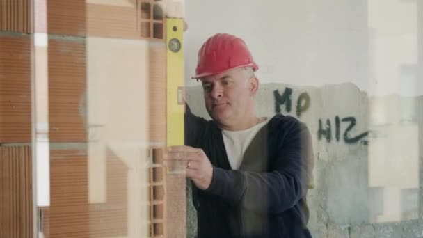 有信心的木匠在工地工作 检查墙面是否平整 在公寓楼里工作的熟练男子 新房的忙碌技术人员 负责房屋的装修和改造 — 图库视频影像
