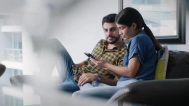 Genç çift cep telefonunu internet ve sosyal medya için kullanıyor. Mutlu adam ve kadın internet sitesi için akıllı telefon tutuyorlar. Karı koca cep telefonundan video izliyorlar.