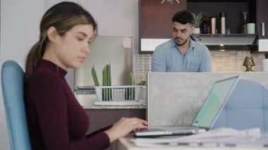 Evde çok ırklı bir çift var: meşgul eş dizüstü bilgisayarla çalışıyor, koca ev işlerini yapıyor. İspanyol iş kadını ofis bilgisayarında yazı yazıyor ve uzaktan iş için e-posta yolluyor, beyaz adam bulaşık yıkıyor.
