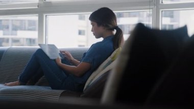 Oturma odasındaki kanepede uzanan genç beyaz kadın eğlence için online filmler ya da televizyon dizileri arıyor. İnternet üzerinden film arayan Latin bir kız.