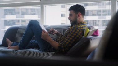 Oturma odasındaki kanepede uzanmış, eğlence olsun diye televizyon dizisi ya da çevrimiçi film arayan genç bir İspanyol. Latin insanlar internet üzerinden film ararlar.