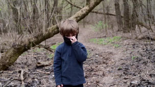 Młody chłopiec w lesie w czarnej masce medycznej wirusa Covid-19 — Wideo stockowe