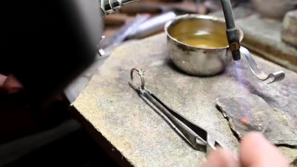 Ювелір у професійній ювелірній майстерні з пальником створює розкішне обручку — стокове відео