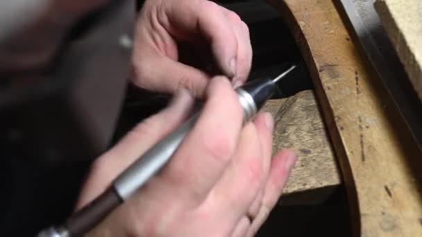 Goudsmid in professionele sieraden workshop graveert trouwring met graveur — Stockvideo