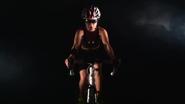 Mujer joven ciclismo bicicleta de carretera, bicicleta de pedaleo, concepto de deporte, estudio negro — Vídeos de Stock