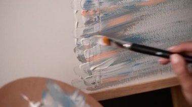 Erkek sanatçı soyut resim, pastel renkler, akrilik boya ve palet çizer.