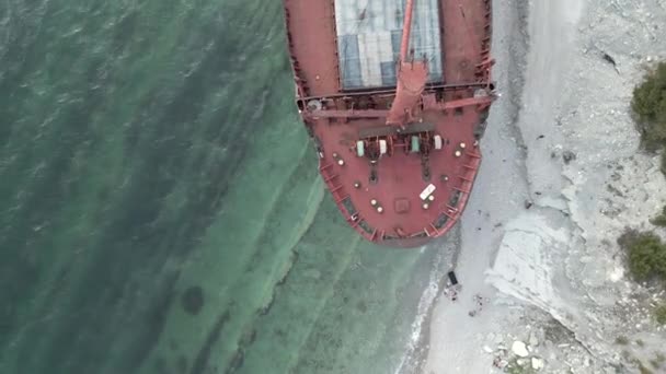 Frachtschiff steht nach gestrandetem Boot am Sandstrand — Stockvideo