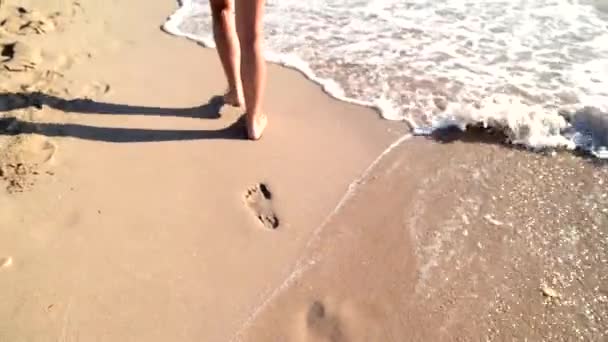 Piernas de mujer joven caminando sobre arena blanca con olas en la playa en la isla, cinemática — Vídeo de stock