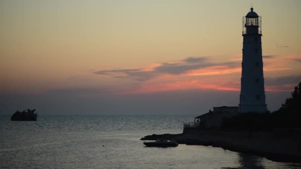 Amazing warna-warni waktu matahari terbenam di laut dekat mercusuar tua dan kapal tenggelam — Stok Video