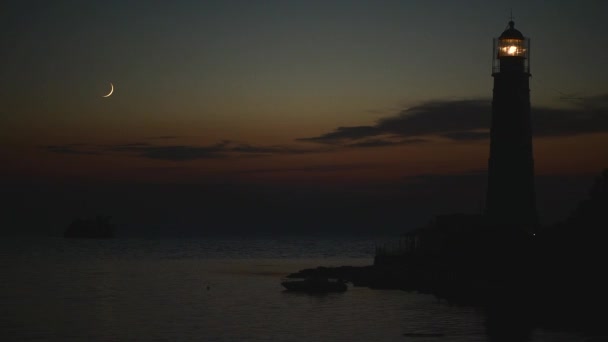 Bulan muda setelah matahari terbenam di laut dekat mercusuar tua dan kapal tenggelam — Stok Video