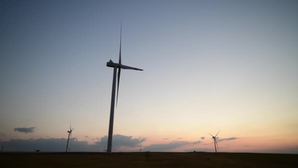 Paisaje vista de la granja molinos de viento, generadores eólicos para la producción de energía en la puesta del sol. Turbinas eólicas generadoras de energía renovable limpia — Vídeo de stock