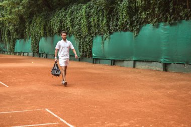 Retro çanta ile eğitimden sonra tenis kortunda yürüyüş sporcu tarz 