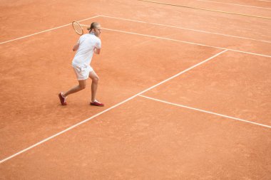 eski moda erkek tenisçi kahverengi tenis kortunda raket ile