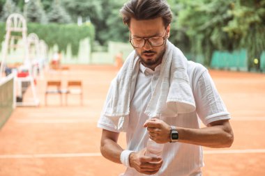 havlu ve şişe suyu tenis kortunda yakışıklı tenisçi