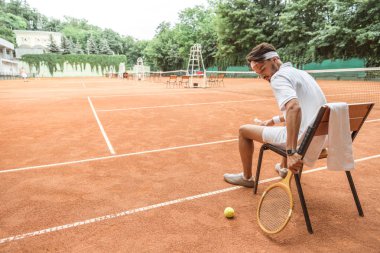 sandalye tenis topu, retro ahşap raket ve havlu ile sahada oturan tenis oyuncusu