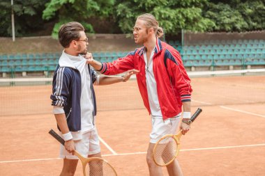 Ahşap raketler çakışan tenis kortunda ile kızgın sporcular