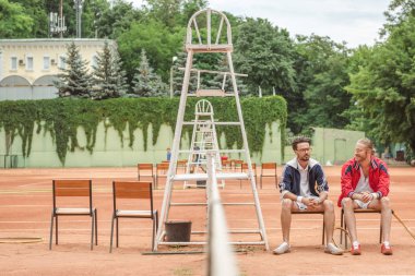 Tenis Kortu sandalyelere oturan Ahşap raketler ile atletik arkadaşlar