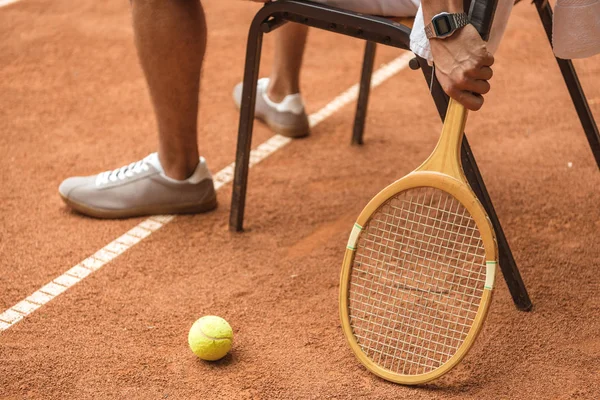 sandalyeye retro ahşap raket ve top ile dinlenme tenis kortunda tenis oyuncusu görünümü kırpılmış