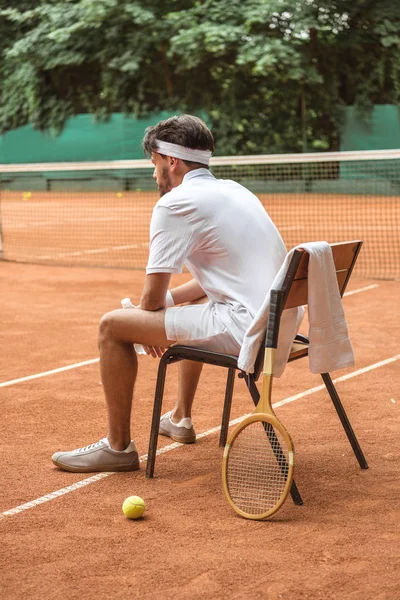 Tenista Sportswear Branco Descansando Cadeira Com Bola Tênis Raquete Madeira — Fotografia de Stock Grátis