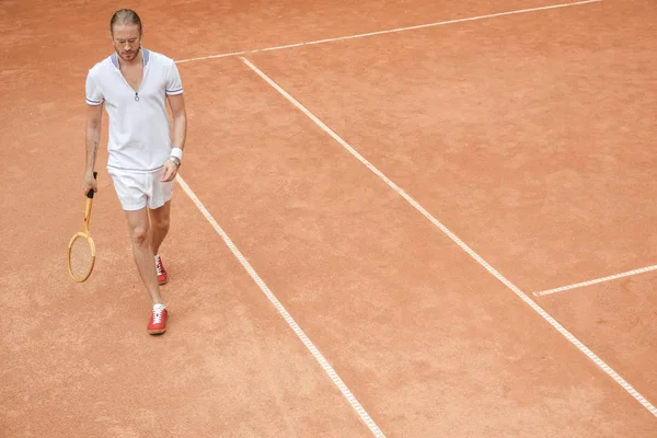 英俊的运动员与网球球拍走在褐色法院 — 免费的图库照片