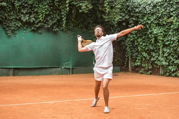 Beau sportif jouant au tennis avec raquette sur le court de tennis — Photo de stock