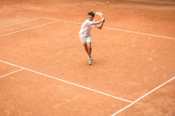 Entrenamiento de jugador de tenis a la antigua con raqueta de madera en la cancha marrón - foto de stock