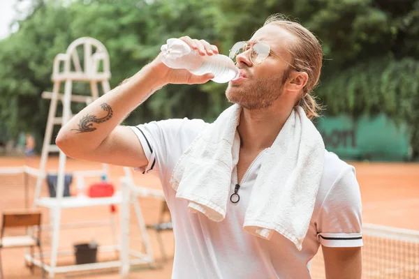 Втомився тенісист питною водою рушник після тренування на тенісний корт — стокове фото