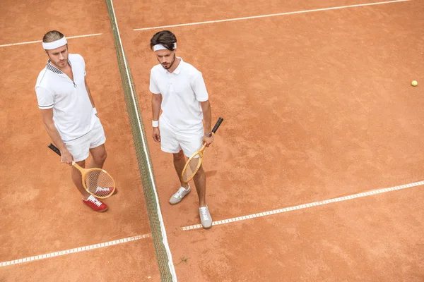 Tennis players in white sportswear with wooden rackets on court — Stock Photo