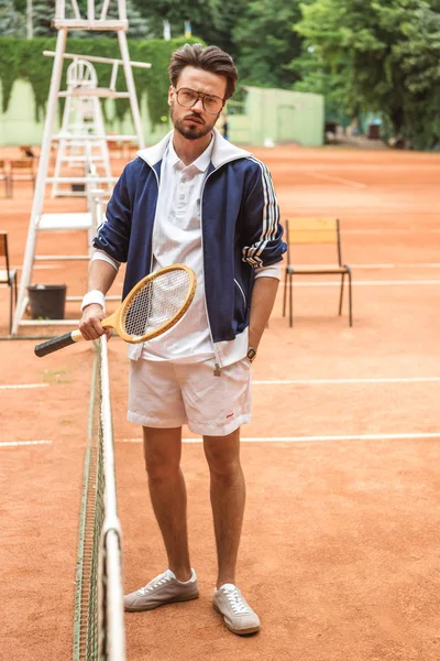 Bonito velho jogador de tênis com raquete na quadra marrom perto da rede de tênis — Fotografia de Stock